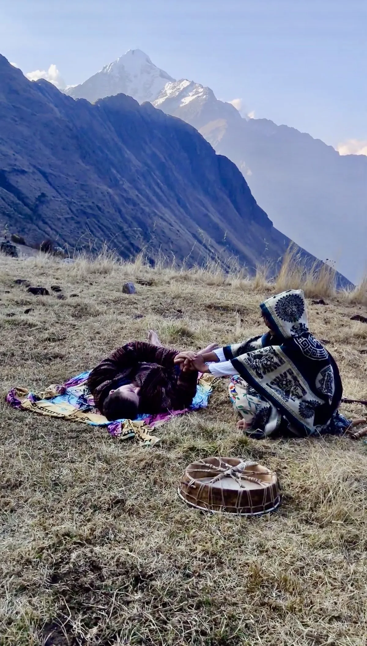 Cérémonie dans les Andes : une personne allongée, Elliot Amaru assis à côté d'elle, un tambour au premier plan