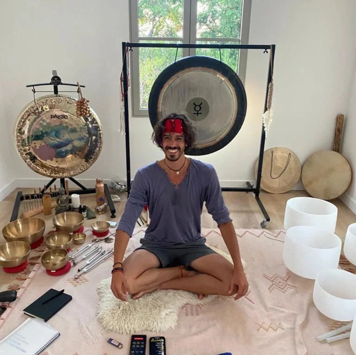 Elliot Amaru sitting among Tibetan bowls, crystal bowls and a gong